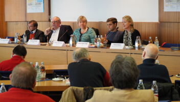 Fünf Personen sitzen auf einem Podium
