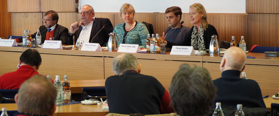 Fünf Personen sitzen auf einem Podium